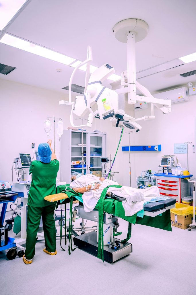 A nurse in a Central Visayas hospital operating room setting adjusting IV equipment during surgery.